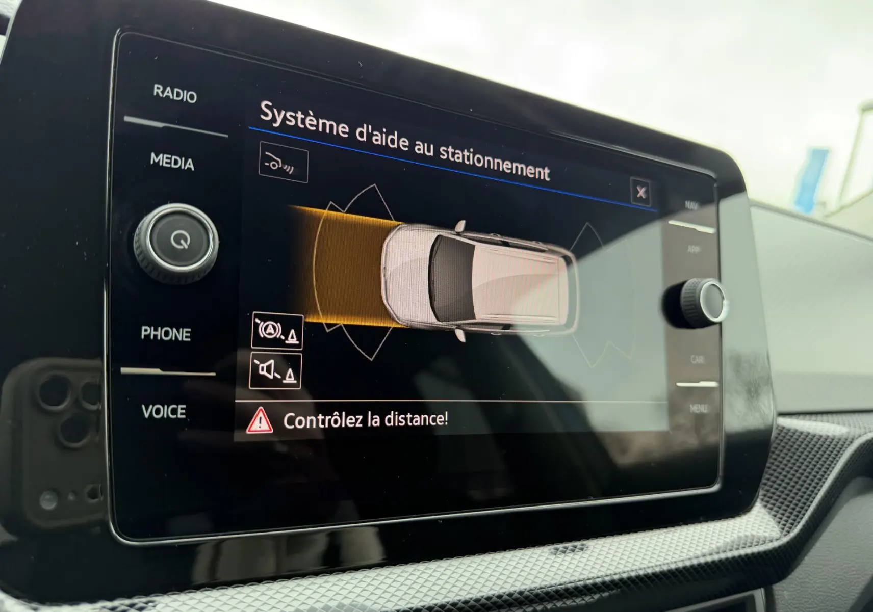 Écran tactile intérieur affichant le système d'aide au stationnement du Volkswagen T-Cross 2025, vue rapprochée.