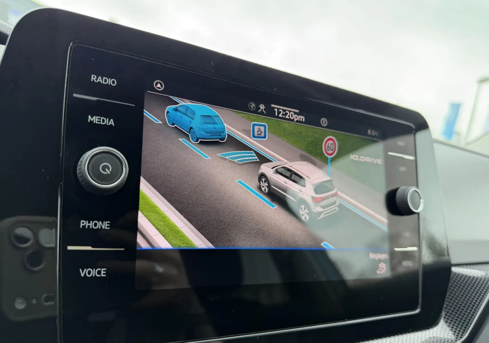 Écran tactile intérieur montrant l’aide au stationnement avec représentation 3D d’un Volkswagen T-Cross bleu et gris.
