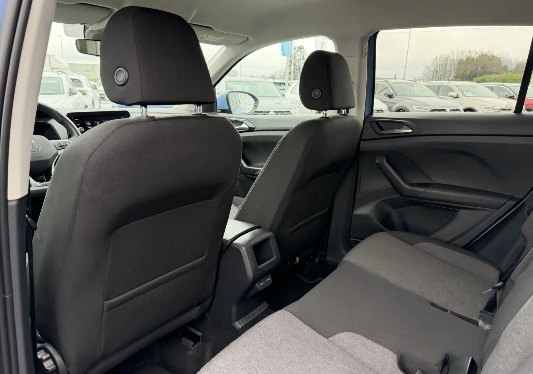Vue intérieure arrière du Volkswagen T-Cross 2025 montrant les sièges tissu noirs et la console centrale entre les sièges avant.