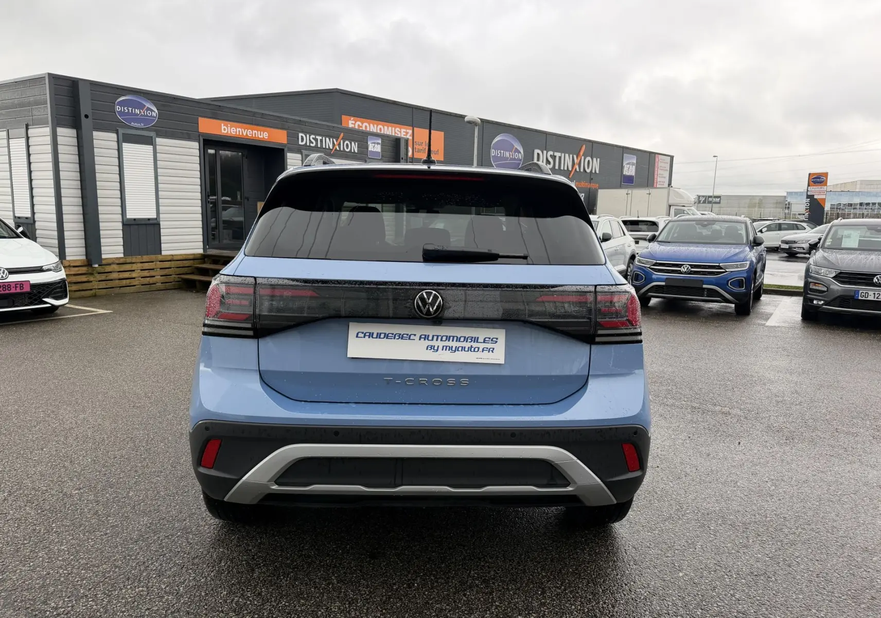 Vue arrière d’un Volkswagen T-Cross bleu 2025 avec feux arrière LED et lunette arrière surteintée, sur parking.