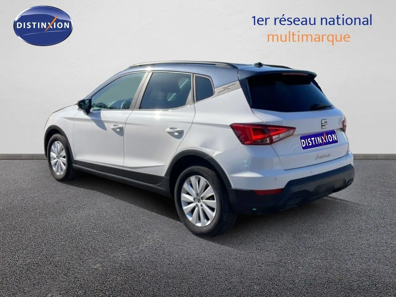 Vue 3/4 arrière droite d'une SEAT Arona blanche métal avec toit noir, sur fond neutre en extérieur.