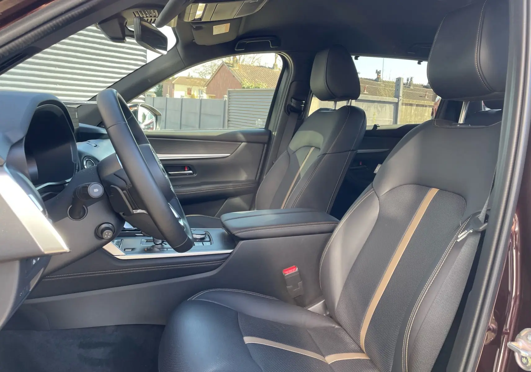 Intérieur du Mazda CX-80 2024 en Artisan Red, vue côté gauche sur sièges cuir noir avec surpiqûres beiges et tableau de bord moderne.