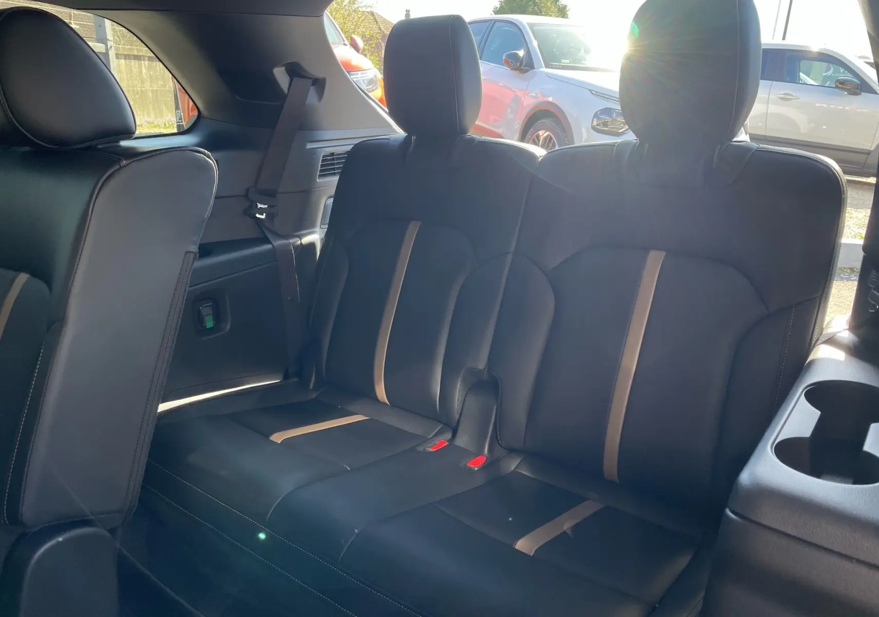 Vue intérieure sur la banquette arrière en cuir noir avec surpiqûres et bandes beiges du Mazda CX-80 2024 Artisan Red.