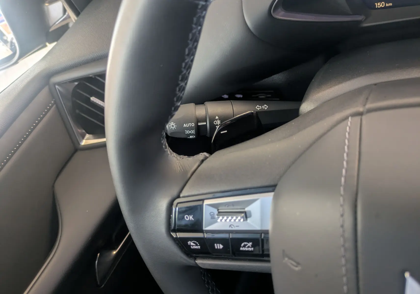 Gros plan sur le volant cuir noir du DS3 2024 avec commandes intégrées et tableau de bord partiellement visible.