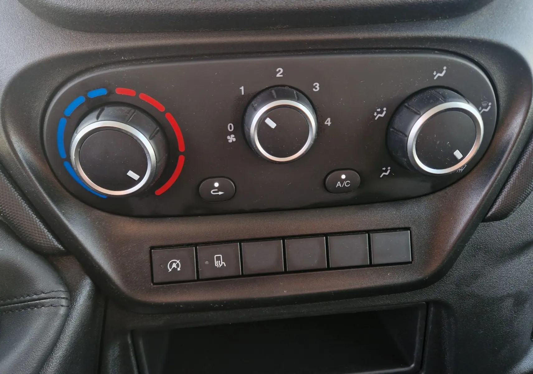 Vue rapprochée des commandes de climatisation du tableau de bord du fourgon Iveco Daily blanc de 2023.