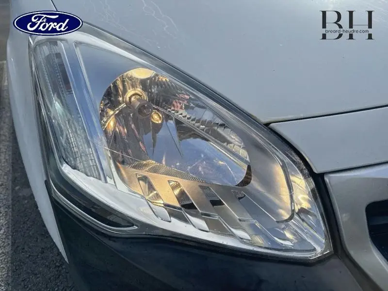 Gros plan sur le phare avant gauche du Peugeot Partner Tepee blanc Banquise, mettant en valeur ses détails lumineux.