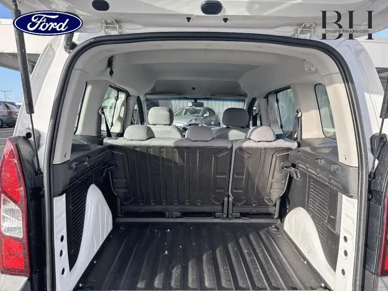 Vue arrière ouverte du Peugeot Partner Tepee blanc Banquise montrant l'espace de chargement et les sièges arrière en tissu.