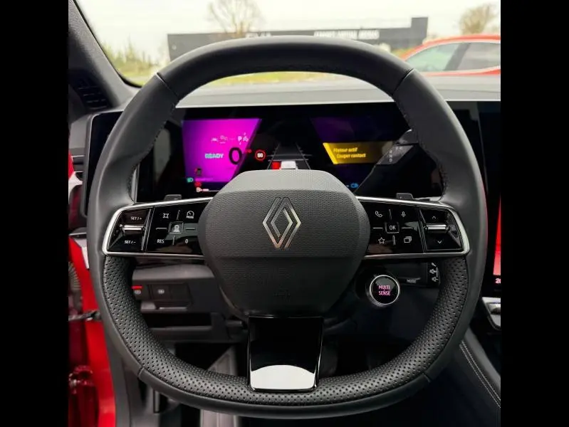 Vue frontale du volant perforé noir avec logo Renault au centre, tableau de bord numérique coloré du Renault Austral rouge flamme 2025.