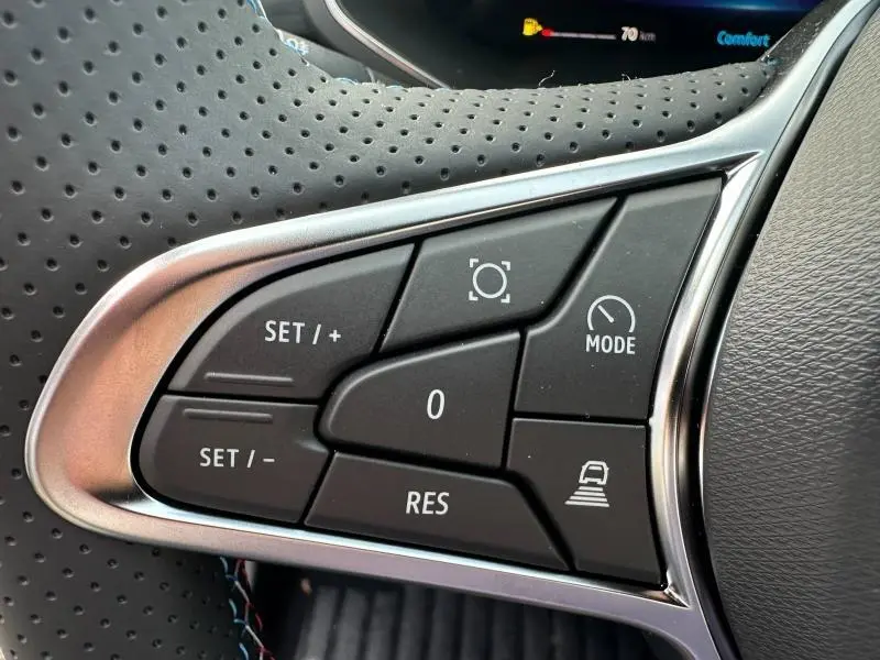 Gros plan sur les commandes au volant du Renault Captur 2026, finition Gris Cassiopée/Noir Étoilé, avec boutons de régulateur et mode conduite.