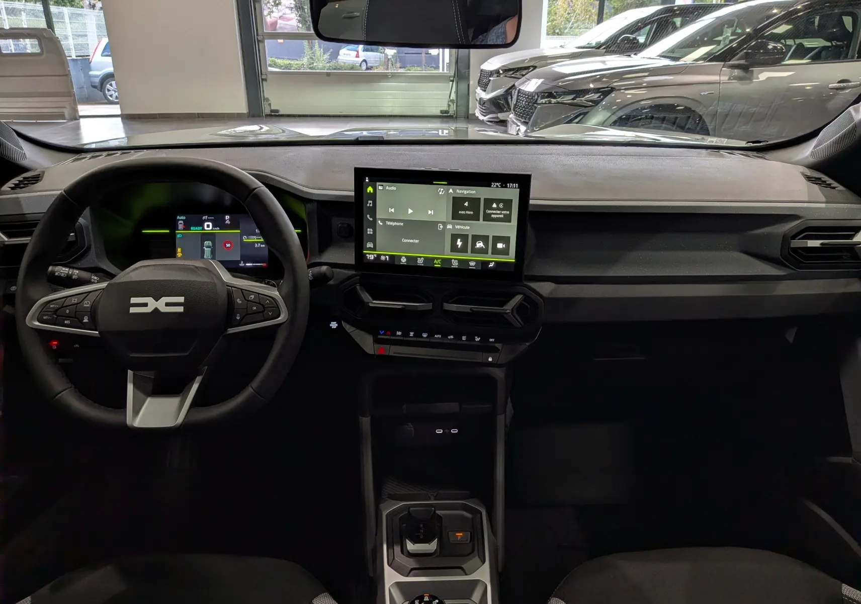 Vue intérieure frontale du tableau de bord du Dacia Duster Hybrid-G 150 CH 4x4 avec écran tactile central et volant multifonction.