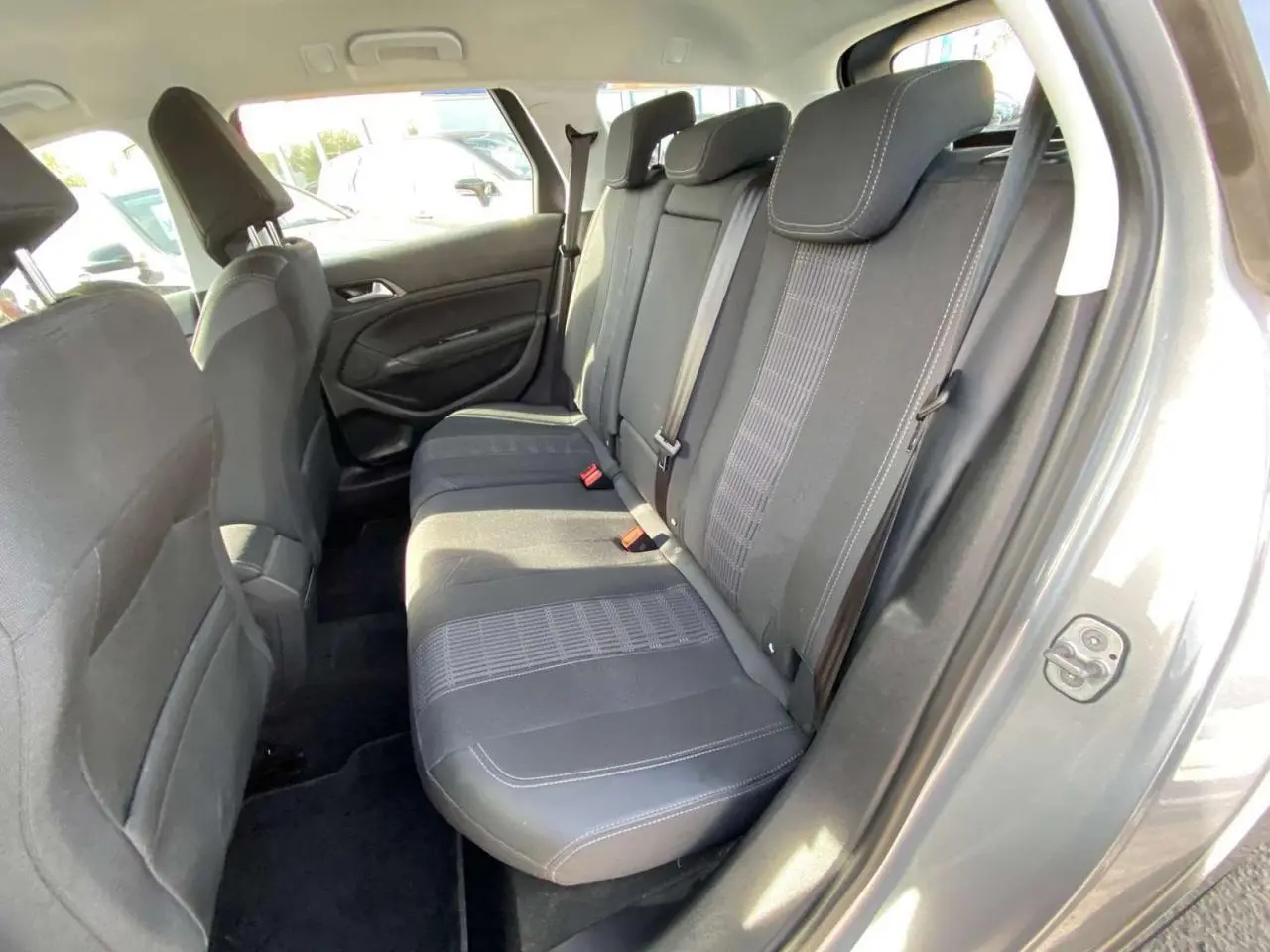 Vue intérieure côté droit sur la banquette arrière noire du Peugeot 308 SW gris Artense 2019 avec ceinture et appuie-têtes.
