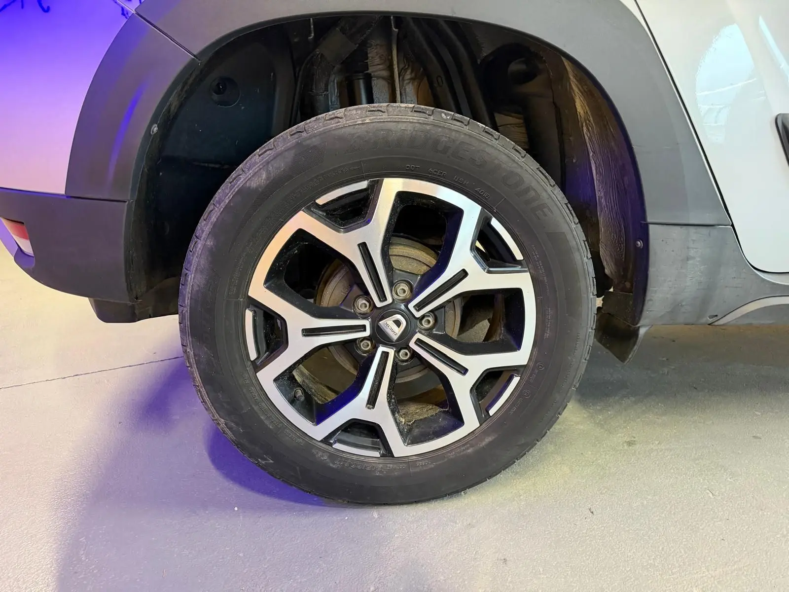 Gros plan sur la roue avant droite du Dacia Duster gris 2019 avec jante alliage 17'' Maldives et logo central.