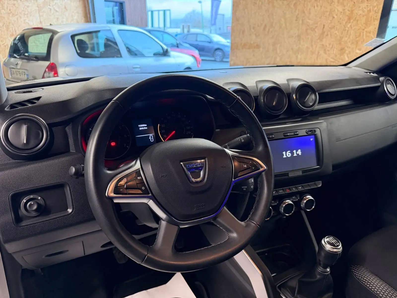 Intérieur du Dacia Duster gris 2019, vue du poste de conduite avec volant, tableau de bord et levier de vitesse manuel.