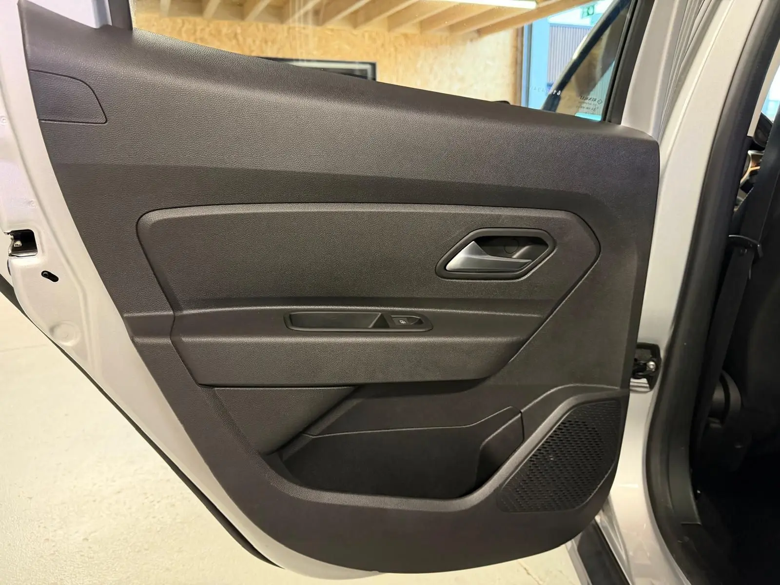 Porte arrière côté gauche du Dacia Duster gris 2019, avec panneau intérieur noir et commande de vitre électrique.