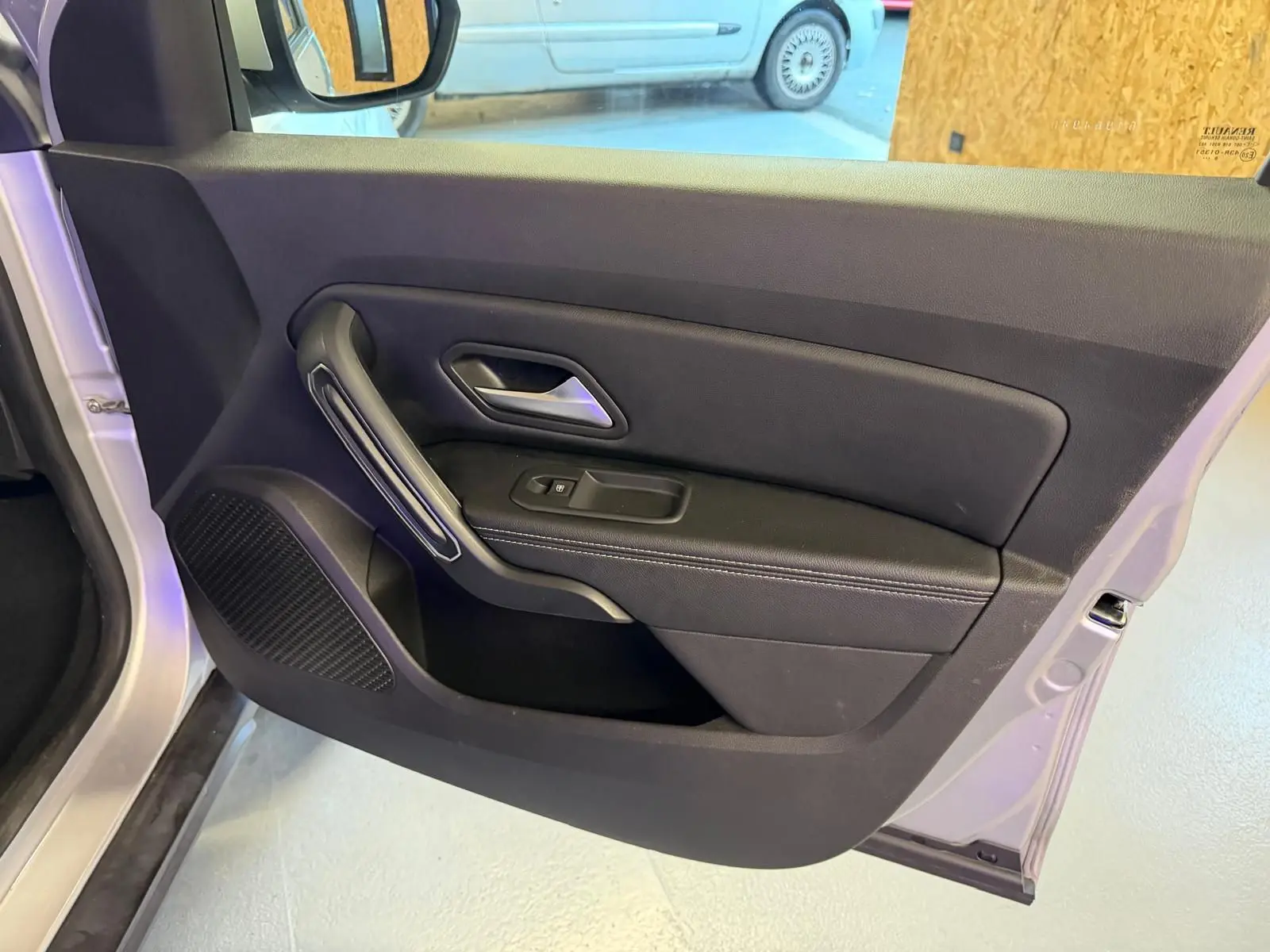 Vue intérieure côté gauche de la porte avant gris clair du Dacia Duster 2019 avec poignée et commande de vitre électrique