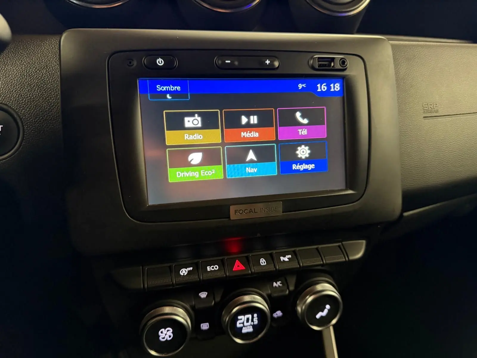 Écran tactile central avec menu coloré et commandes de climatisation du tableau de bord du Dacia Duster gris 2019.