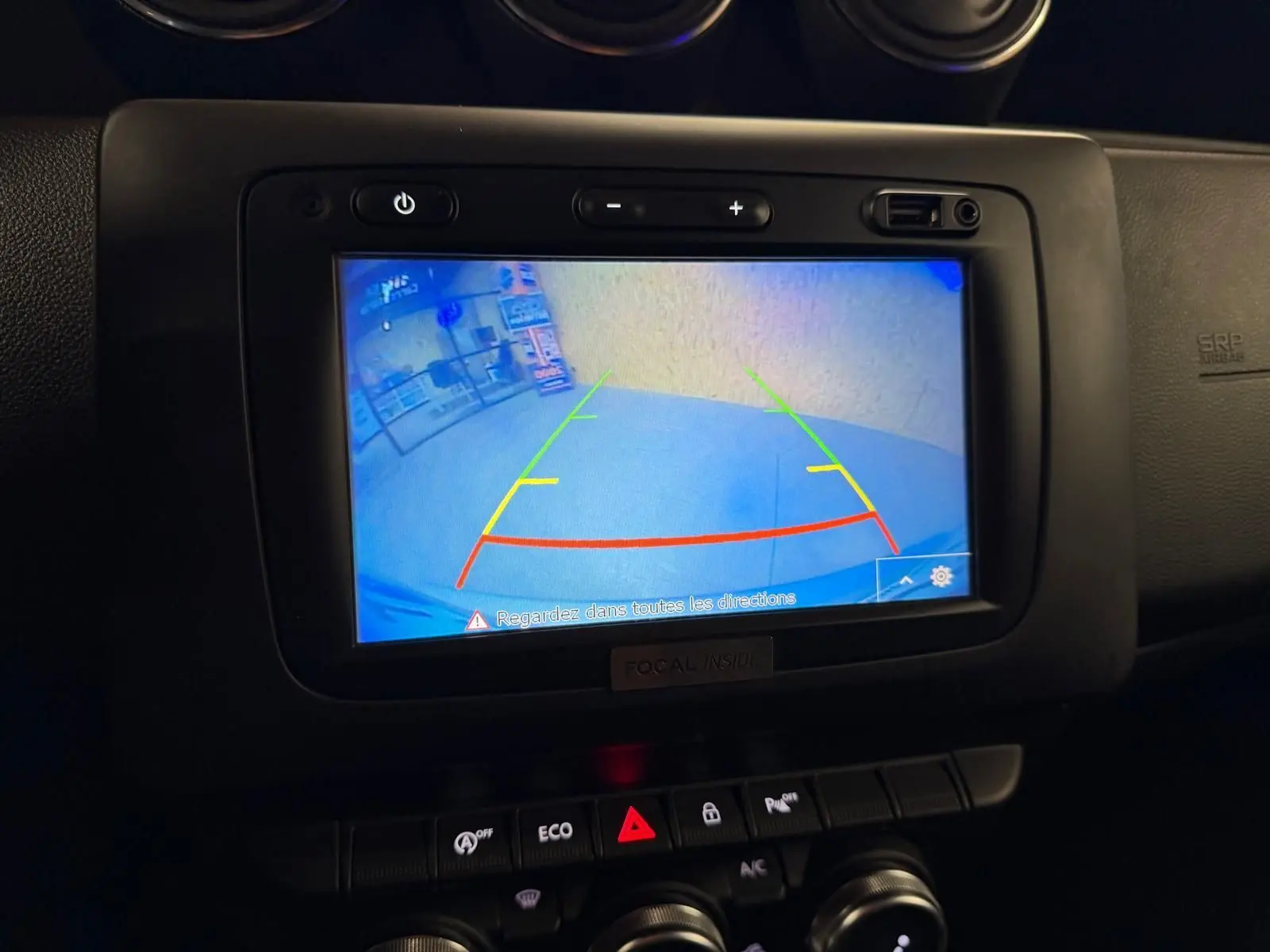 Écran de caméra de recul du Dacia Duster 2019 affichant les lignes de guidage colorées dans l'habitacle noir.