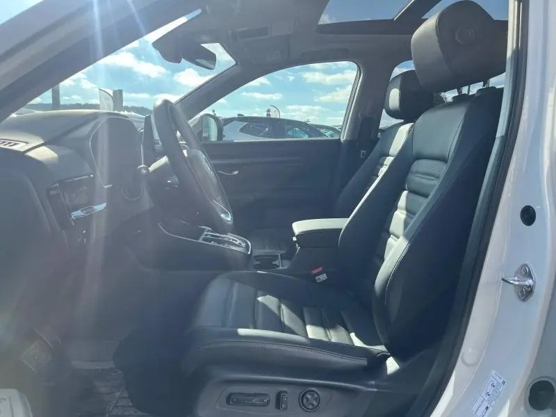 Vue intérieure côté conducteur du Honda CR-V 2024 avec sièges cuir noir et toit panoramique lumineux.
