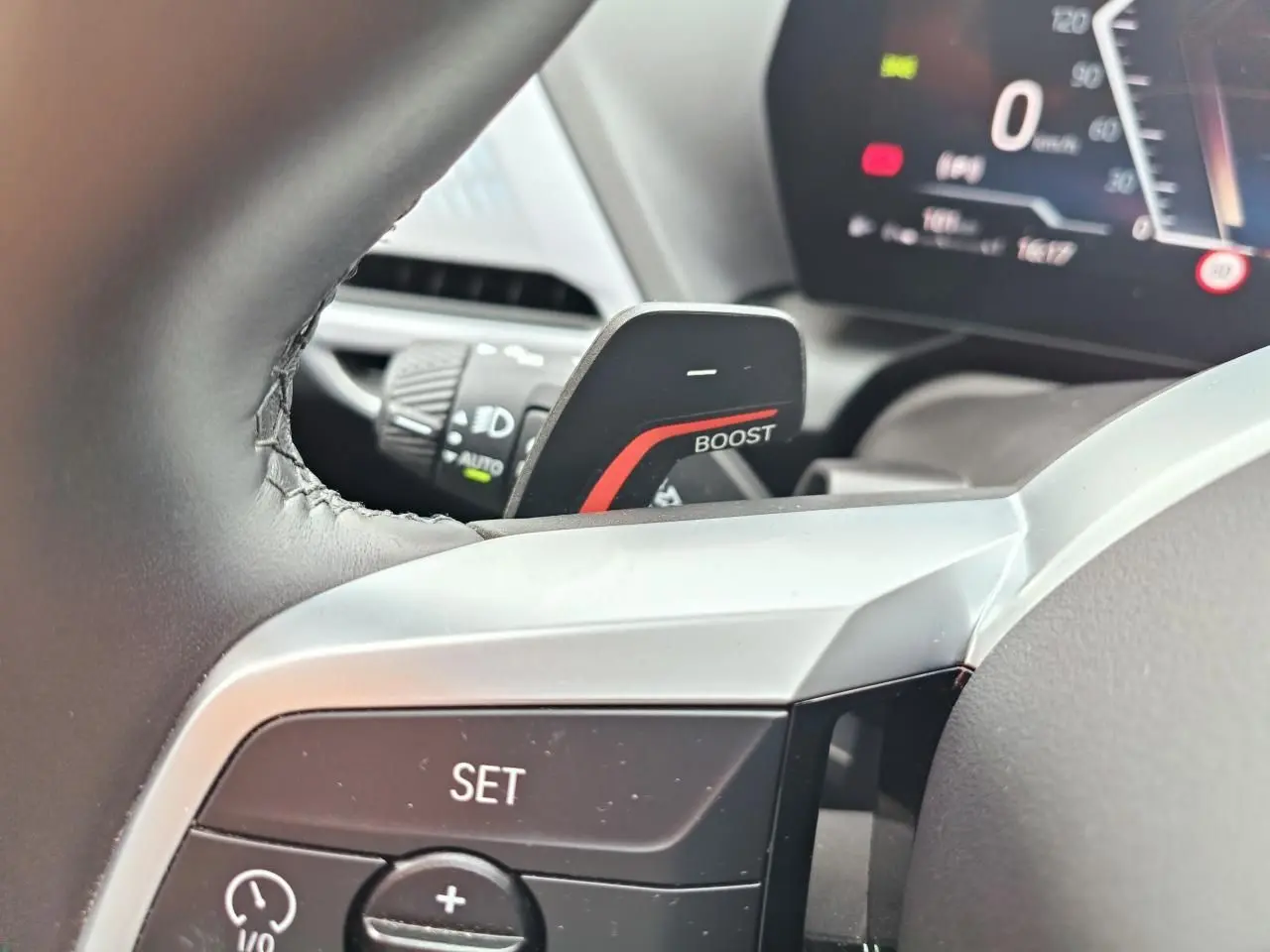 Gros plan sur la palette "BOOST" et les commandes au volant de la BMW Série 1 F70 gris Skyscraper, intérieur moderne.