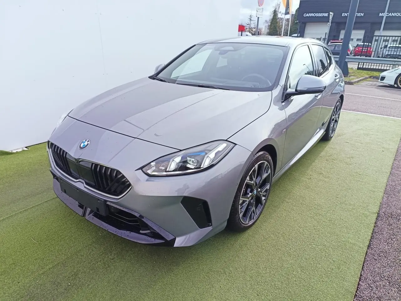 BMW Série 1 gris Skyscraper vue 3/4 avant droit avec toit noir et jantes alliage 18 pouces M Sport.