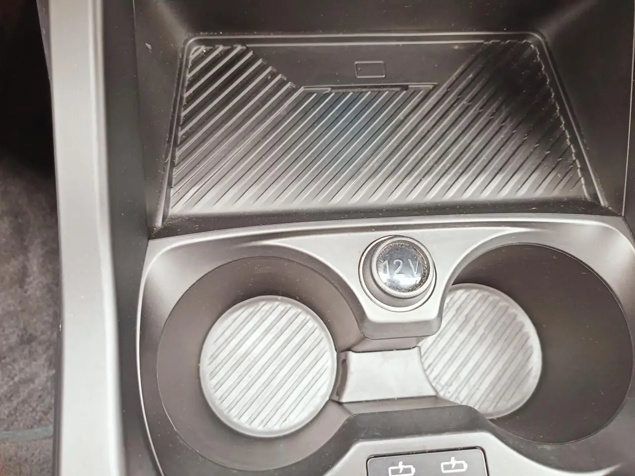 Gros plan sur la console centrale de la BMW Série 1 F70 120 M Sport, montrant les porte-gobelets et prise 12V.