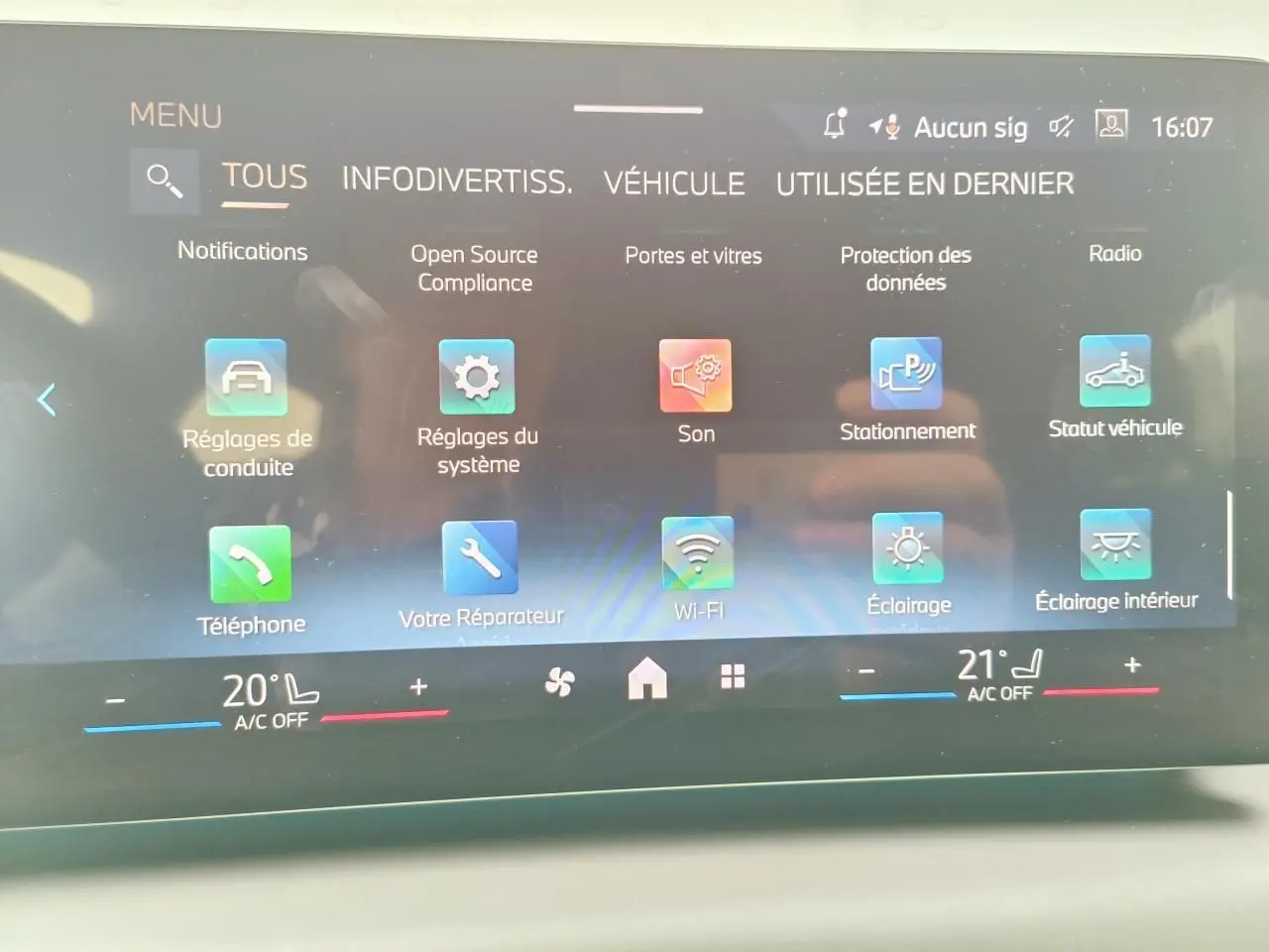 Écran tactile intérieur de la BMW Série 1 2025 affichant le menu principal avec options connectées et climatisation bi-zone.