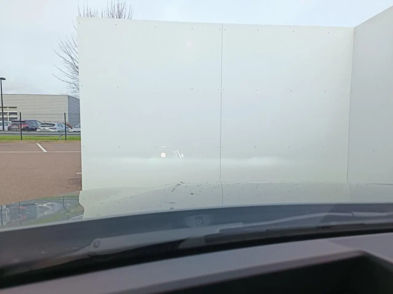 Vue depuis l’intérieur de la BMW Série 1 2025, toit gris Skyscraper avec affichage tête haute projeté sur le pare-brise.