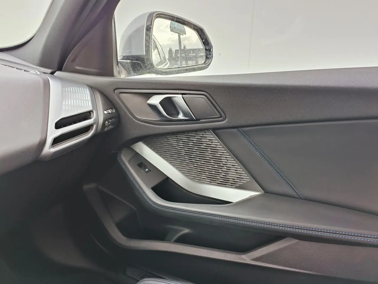 Vue intérieure côté droit de la porte BMW Série 1 F70 avec insert aluminium graphite et surpiqûres bleues.
