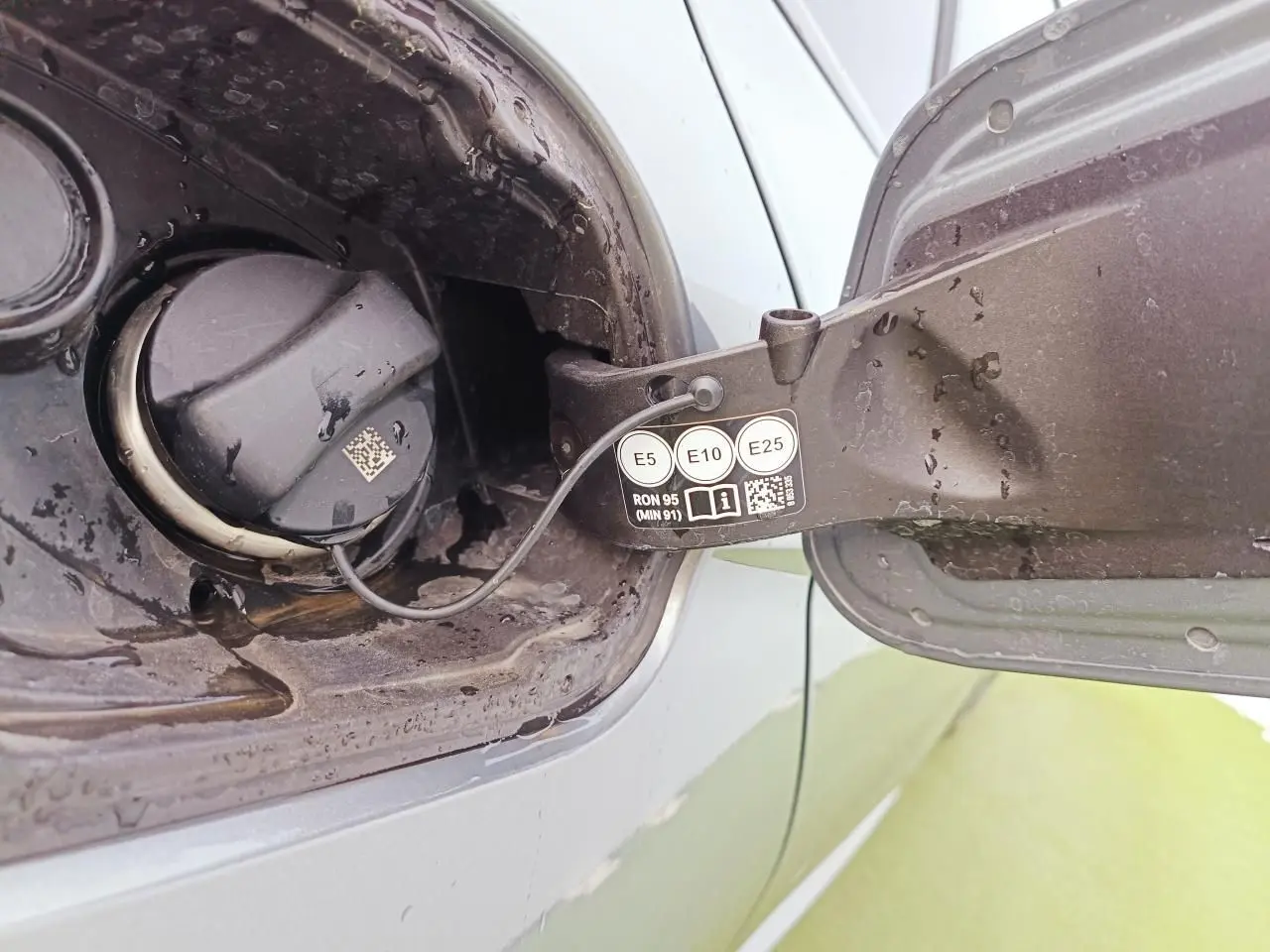 Gros plan sur la trappe à carburant ouverte d’une BMW Série 1 gris Skyscraper avec bouchon essence visible.