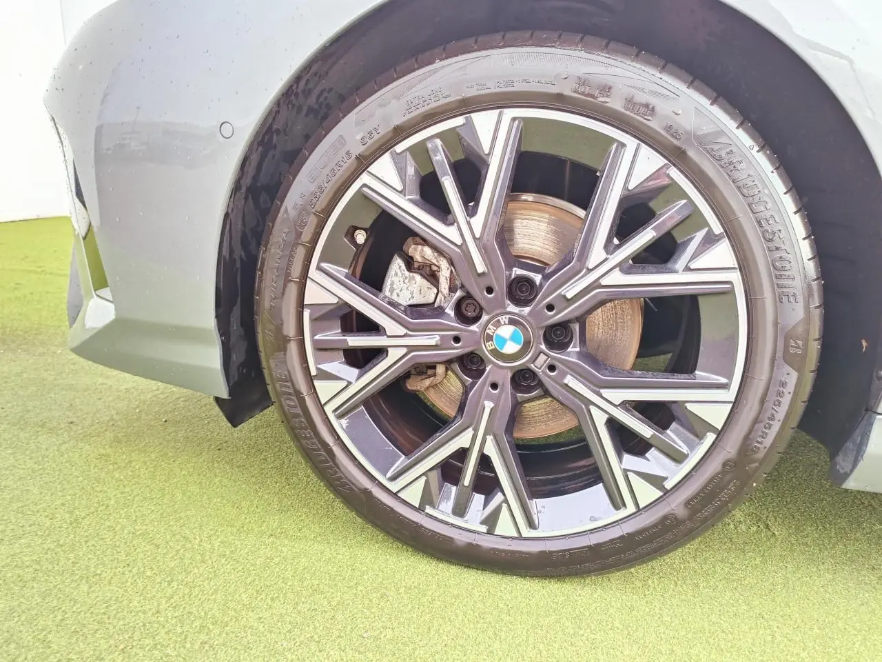 Gros plan sur la roue avant gauche d'une BMW Série 1 gris Skyscraper avec jante alliage 18 pouces style 975 M bicolore.