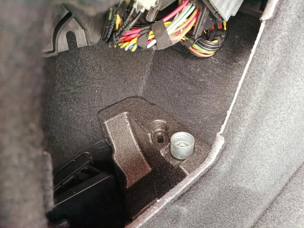 Gros plan sur l'intérieur du coffre de la BMW Série 1 F70 120 M Sport, montrant câblage et revêtement noir.