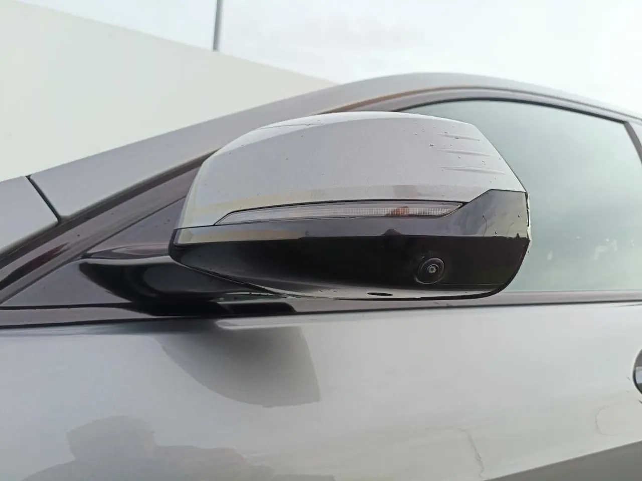 Gros plan sur le rétroviseur droit gris Skyscraper avec caméra intégrée sur BMW Série 1 2025 toit noir.