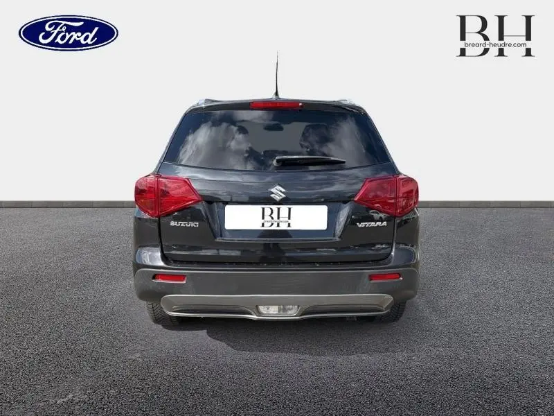 Vue arrière d'un Suzuki Vitara Cosmic Black Pearl métallisé avec feux arrière rouges et lunette arrière teintée.