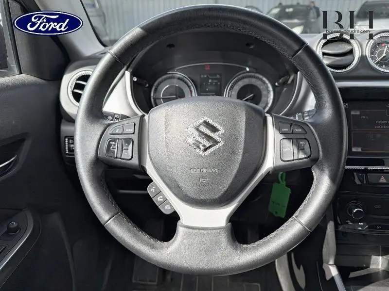 Vue rapprochée du volant cuir noir de Suzuki Vitara 2019 avec commandes intégrées et tableau de bord visible.