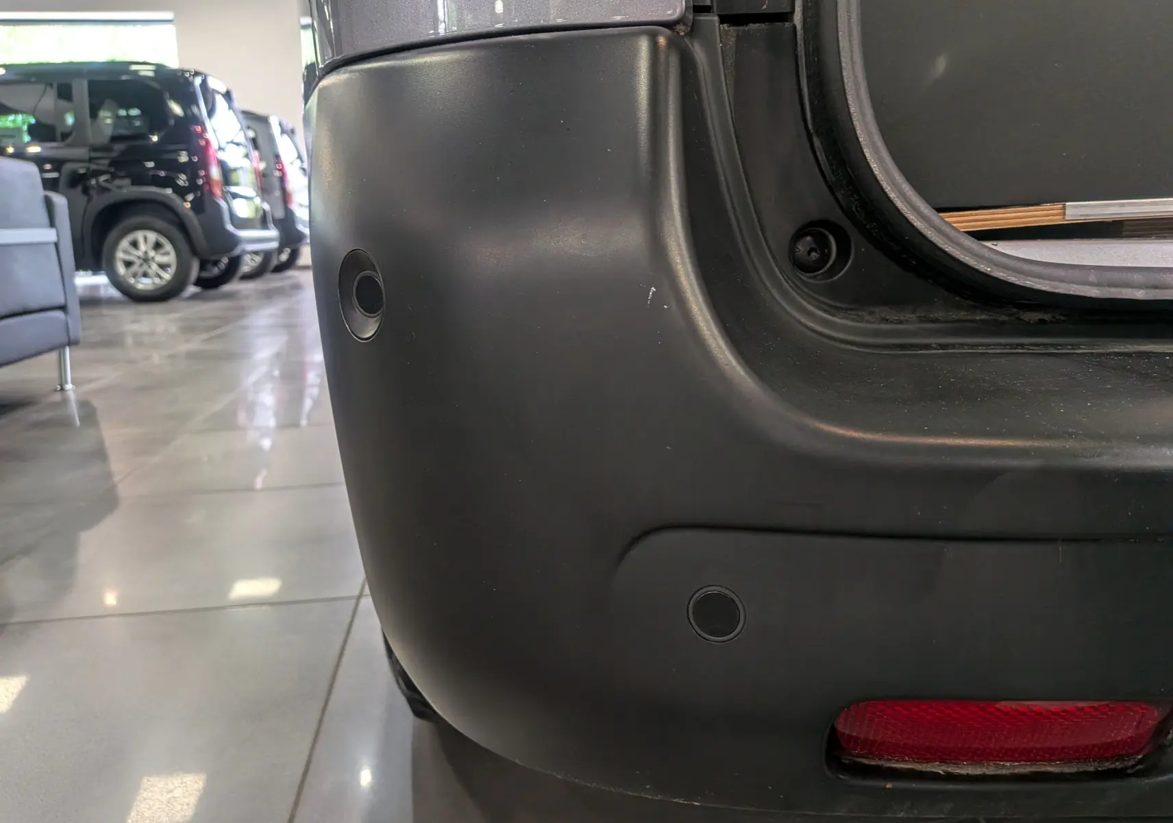 Gros plan sur l’angle arrière droit du Peugeot Expert Fourgon gris acier, mettant en valeur le pare-chocs avec capteurs de recul.