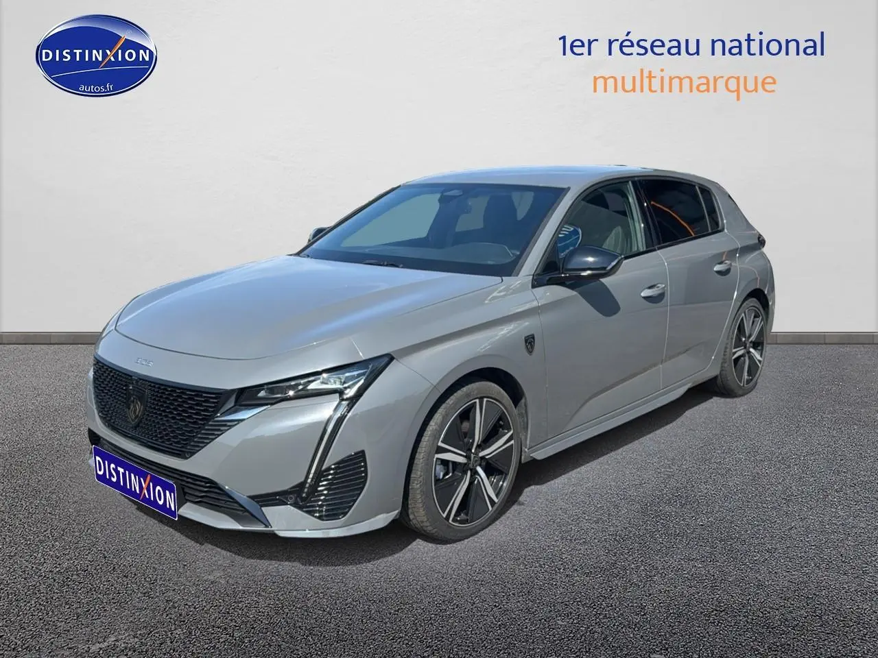Peugeot 308 gris vue 3/4 avant droit, avec jantes alu et calandre noire distinctive.