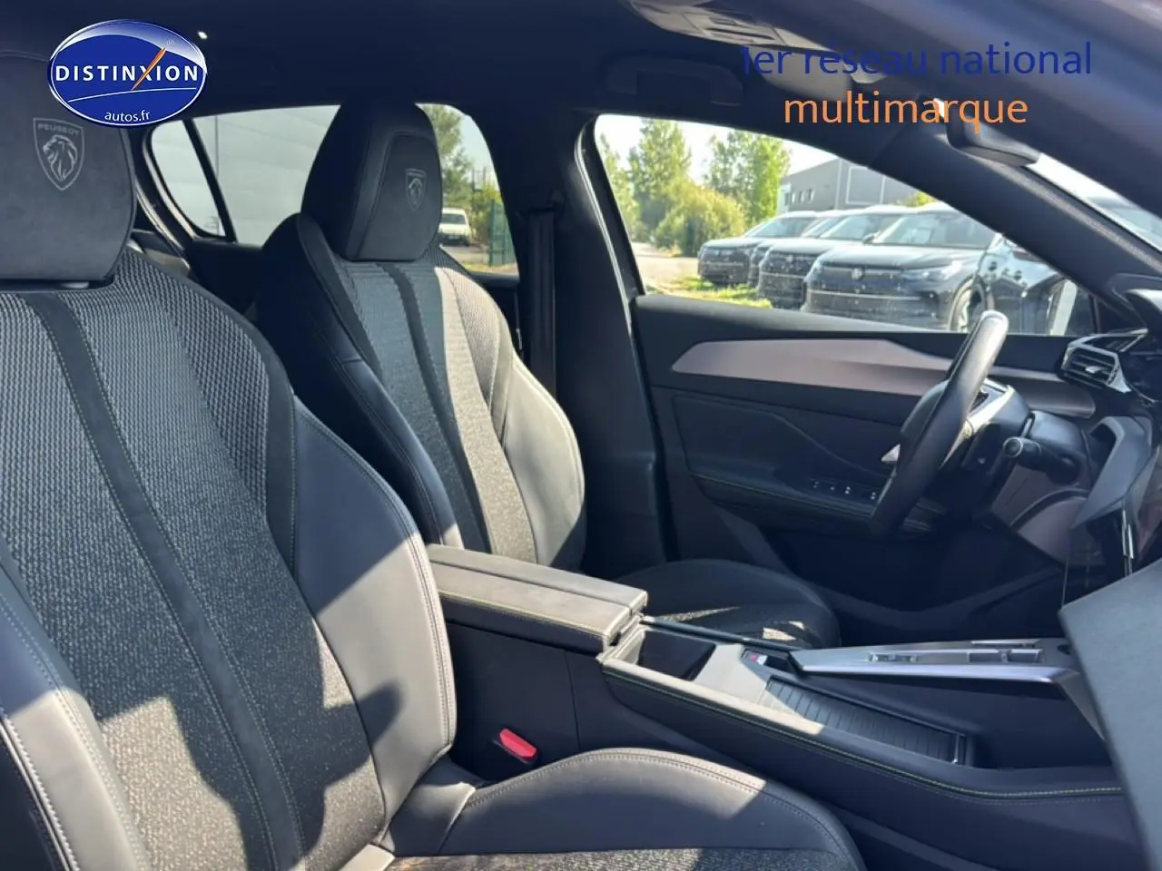 Vue intérieure côté droit de la Peugeot 308 gris, mettant en valeur les sièges sport avec logo Peugeot brodé et accoudoir central.