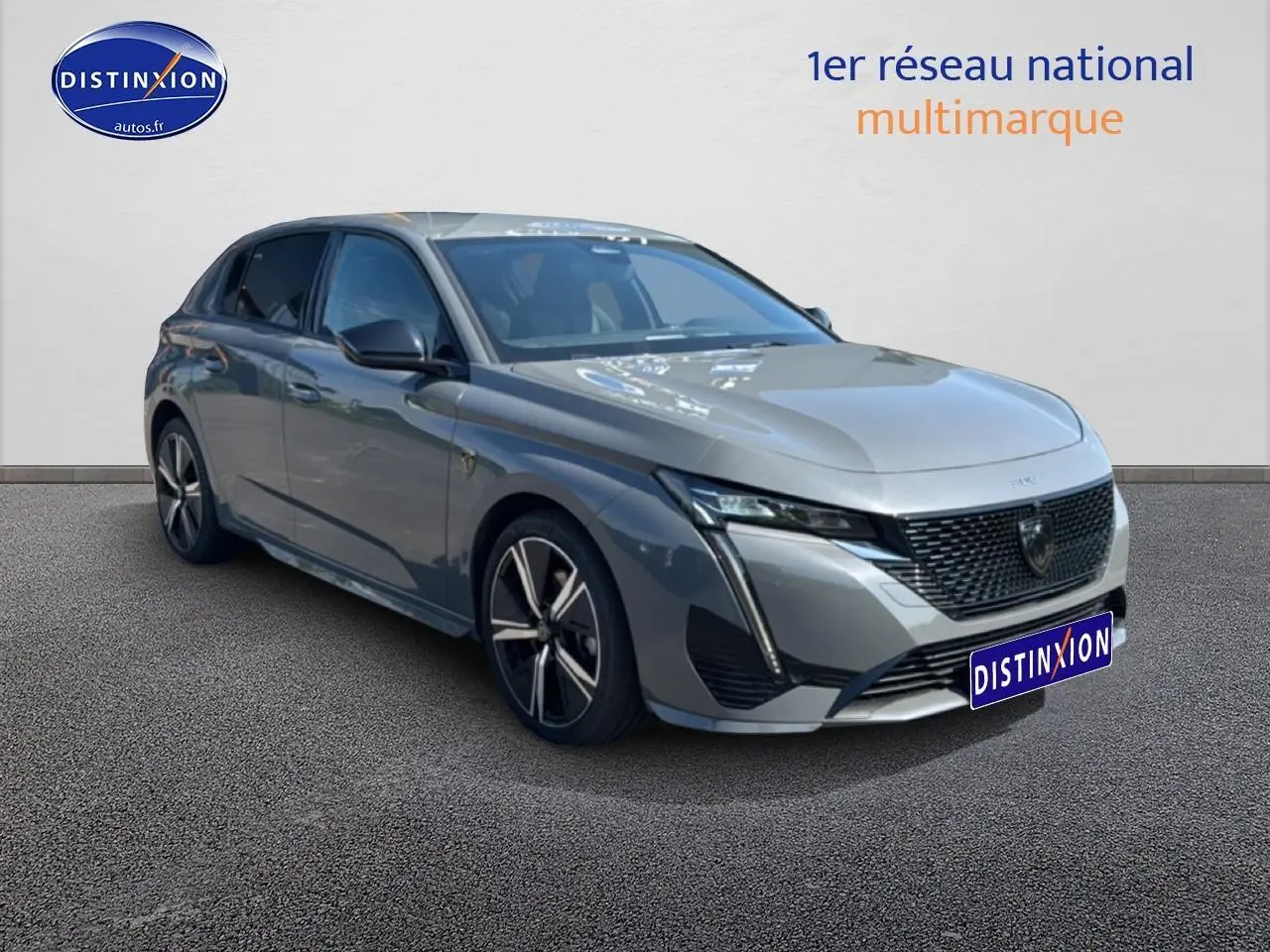 Peugeot 308 gris 3/4 avant droit, avec calandre noire et jantes alliage distinctives.
