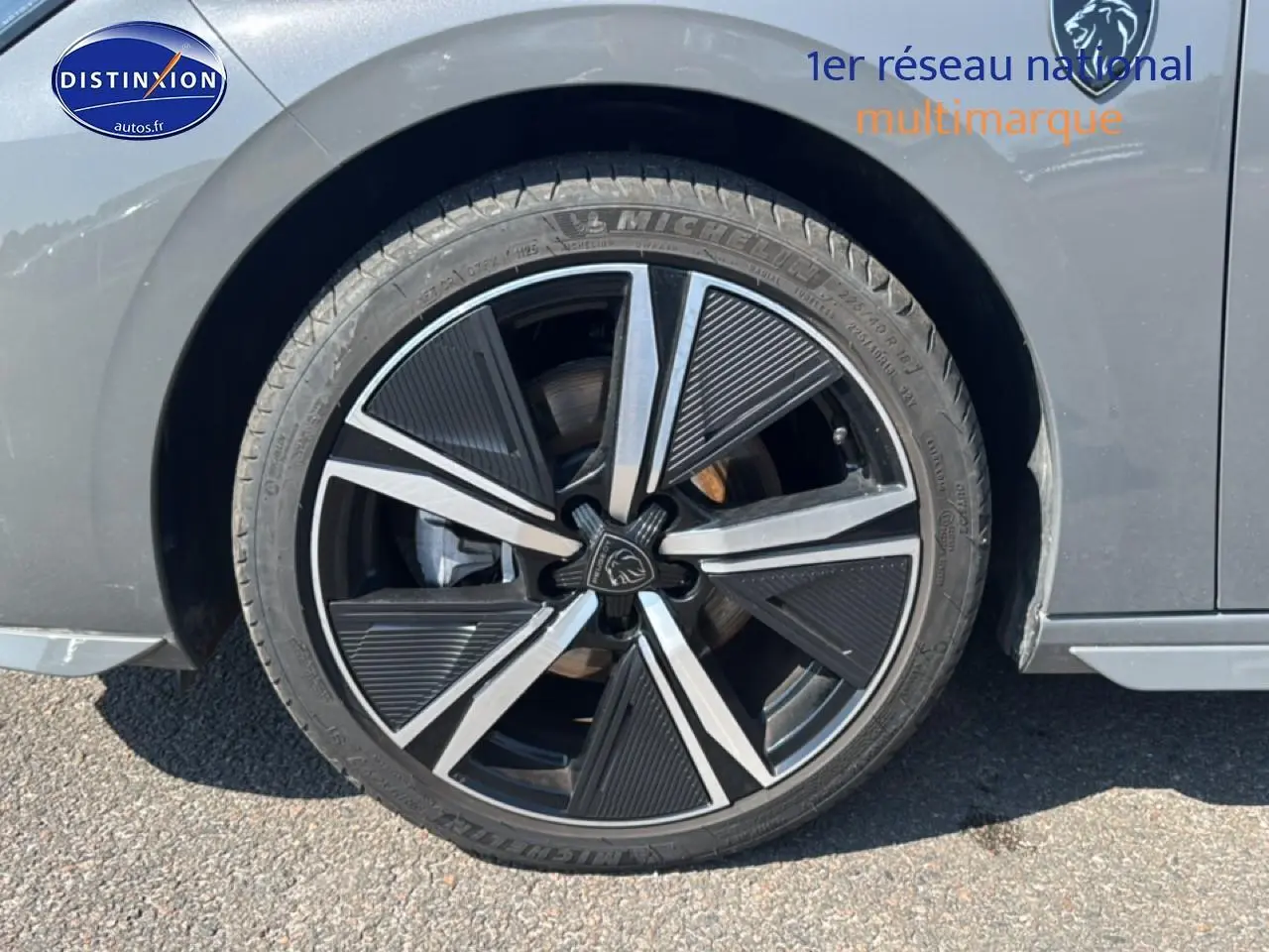 Gros plan sur la roue avant gauche d'une Peugeot 308 gris métallisé avec jante alu noire et argentée.