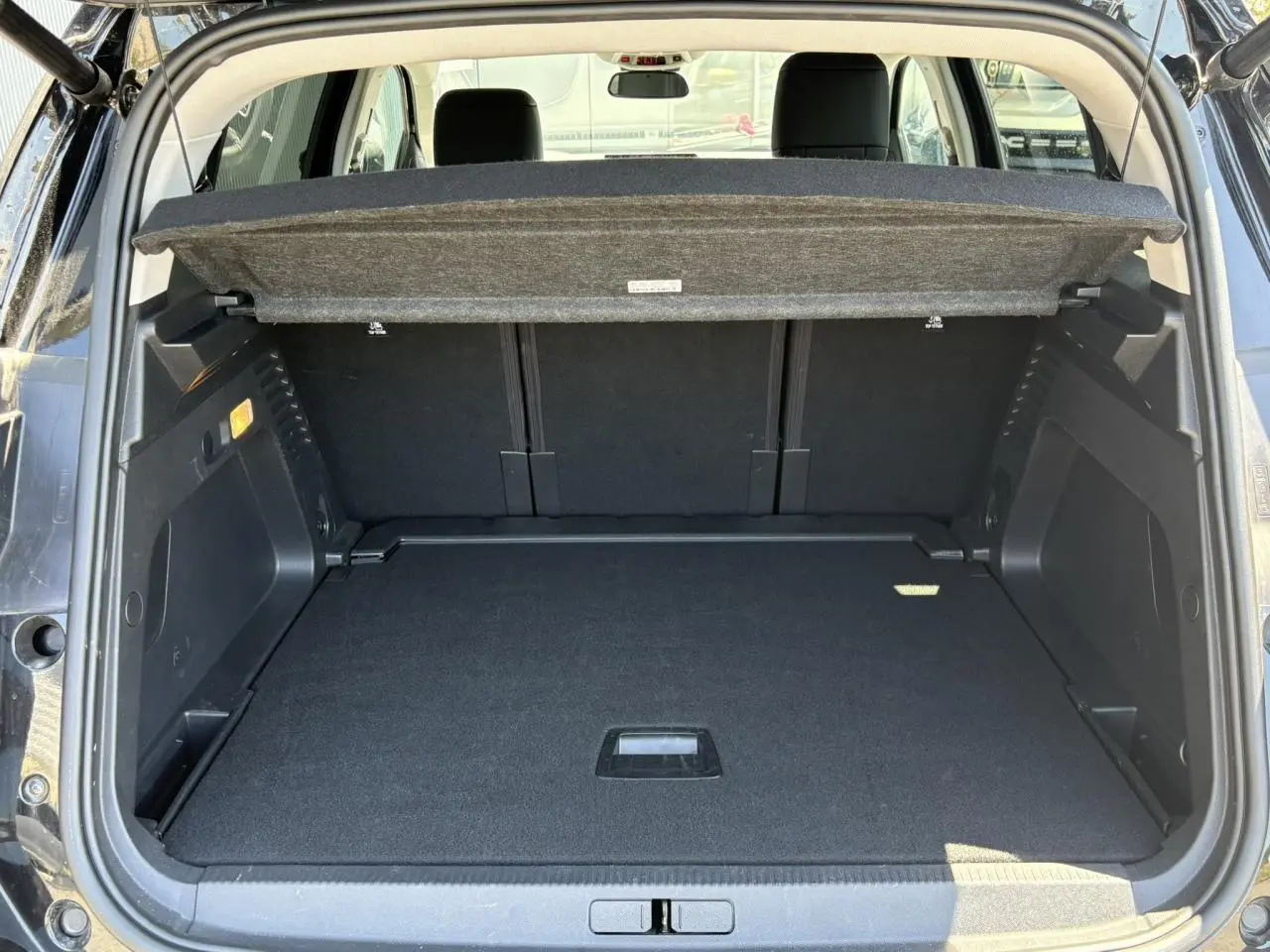 Coffre ouvert vu de l'arrière du Citroën C5 Aircross Hybrid noir Perla, avec cache-bagages relevé et espace de rangement vide.