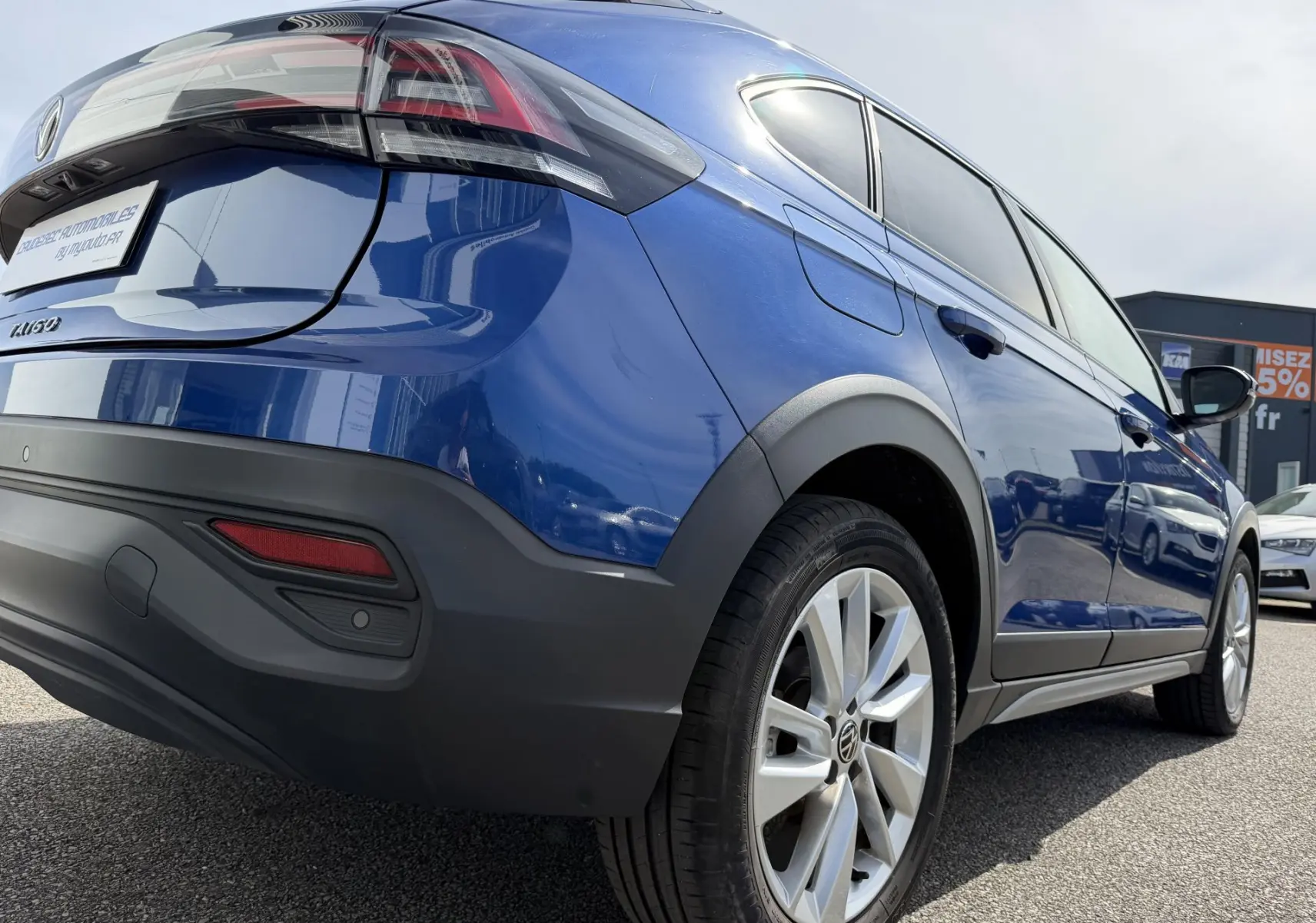 Vue 3/4 arrière droite du Volkswagen Taigo bleu métallisé avec jantes alliage et protections noires sur les passages de roues.