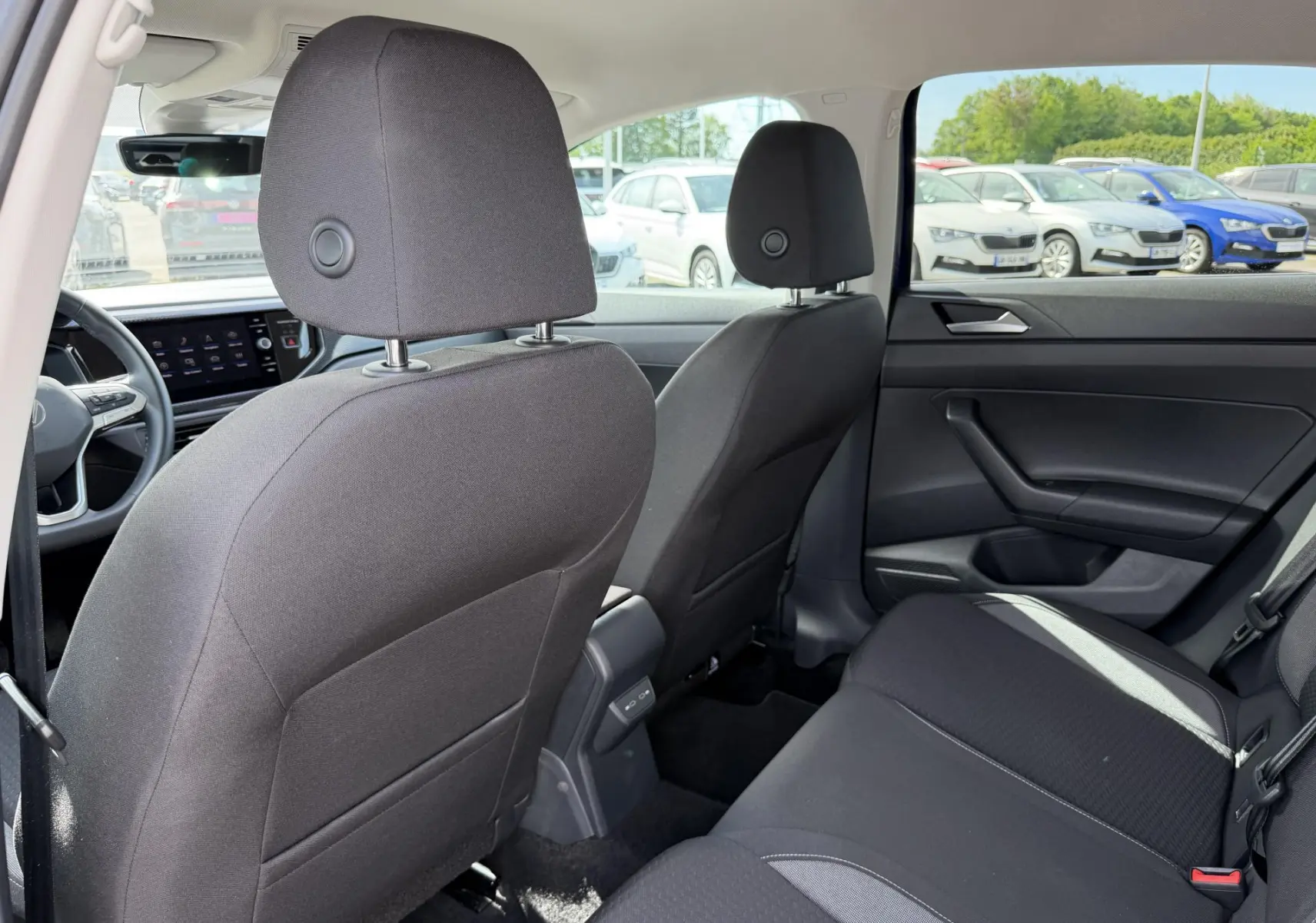 Vue intérieure arrière du Volkswagen Taigo 2025 montrant les sièges noirs et la portière côté droit.