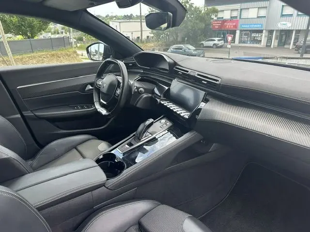 Intérieur noir de la Peugeot 508 SW 2020, vue côté conducteur montrant le tableau de bord et la console centrale moderne.