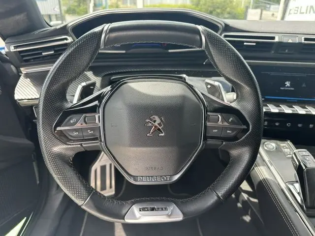 Vue rapprochée du volant cuir noir de la Peugeot 508 SW 2020, avec commandes intégrées et tableau de bord moderne.
