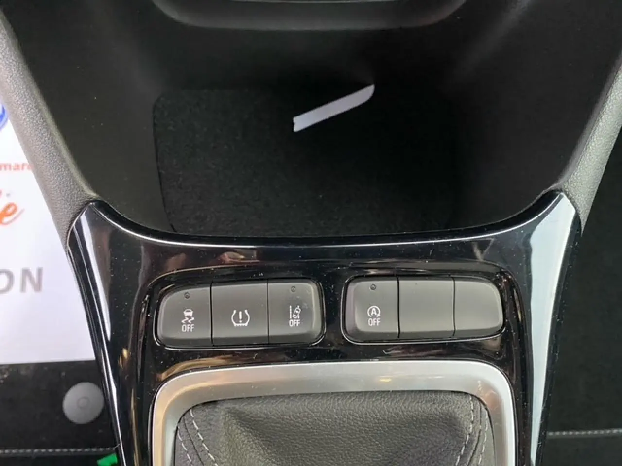 Gros plan sur la console centrale noire brillante avec commandes d'assistance et levier de vitesse en cuir.