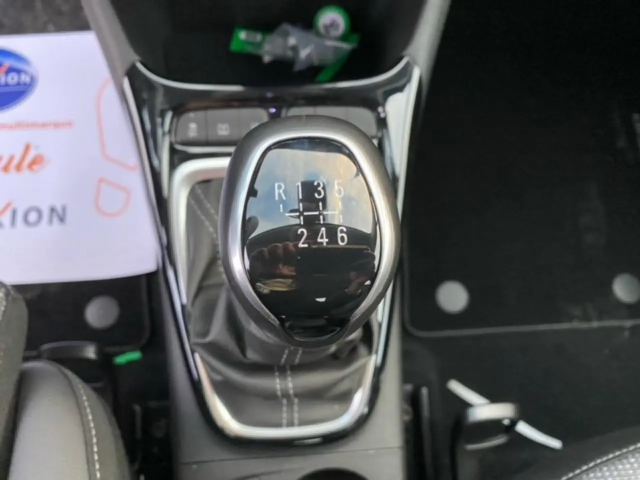 Le levier de vitesse manuel noir brillant de l'Opel Crossland 1.2i Turbo, vu en gros plan depuis l'intérieur.