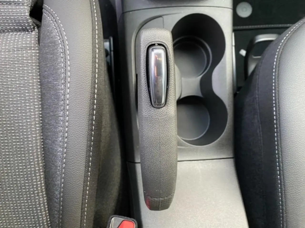 Vue rapprochée du frein à main et porte-gobelets entre les sièges avant noirs de l'Opel Crossland gris alu 2022.