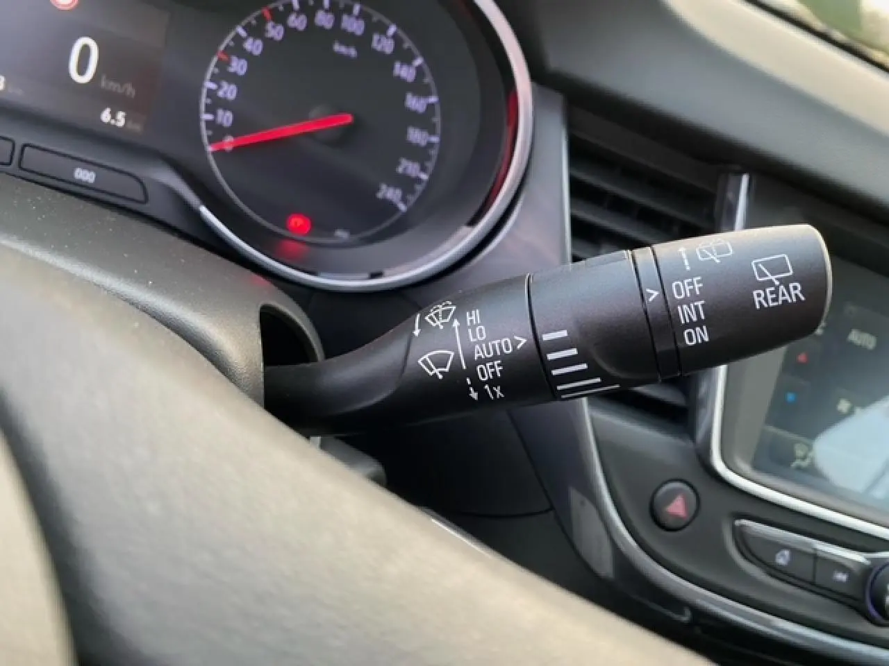 Gros plan sur la commande des essuie-glaces à gauche du volant dans l'habitacle de l'Opel Crossland gris alu 2022.