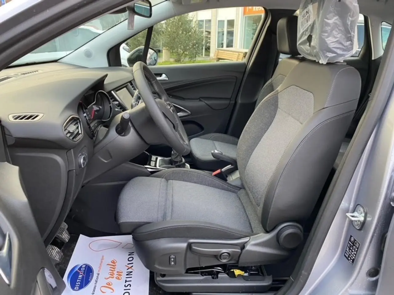 Vue intérieure côté conducteur de l’Opel Crossland gris alu 2022, sièges tissu gris et tableau de bord moderne.
