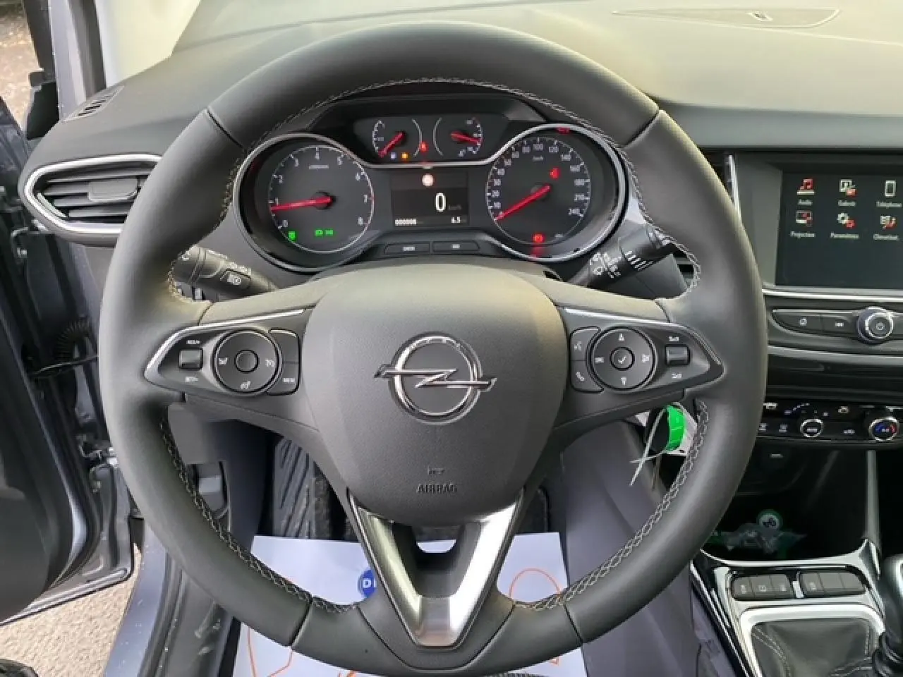 Vue rapprochée du volant multifonction d'une Opel Crossland gris alu 2022, avec tableau de bord et écran tactile visibles.